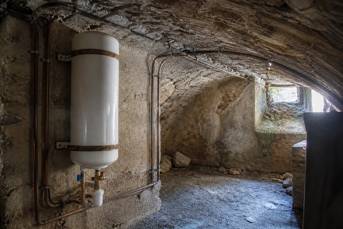 Chauffe-eau et raccords cuivre apparents dans la cave voûtée d’une maison de bourg du Sancerrois